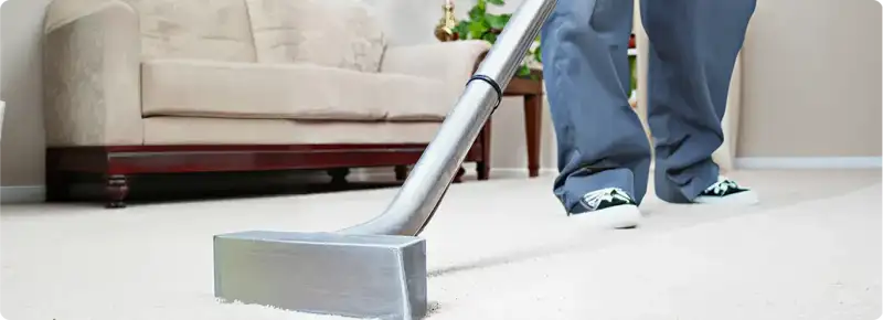 Carpet cleaning technician using a hot-water extraction wand on a light-colored carpet in a living room, Charleston, SC.