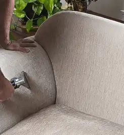 Professional upholstery cleaner deep-cleaning a fabric sofa with a handheld extraction tool and hose Charleston, SC.
